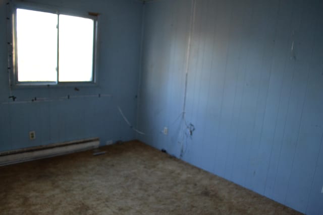 carpeted spare room with a baseboard heating unit