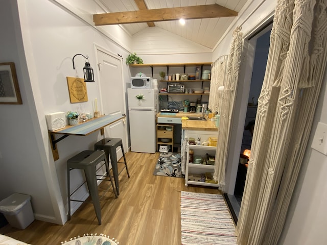 kitchen featuring white appliances, sink, light hardwood / wood-style flooring, vaulted ceiling with beams, and wood ceiling