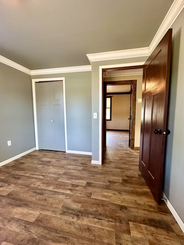 unfurnished bedroom featuring dark wood-type flooring, a closet, and ornamental molding