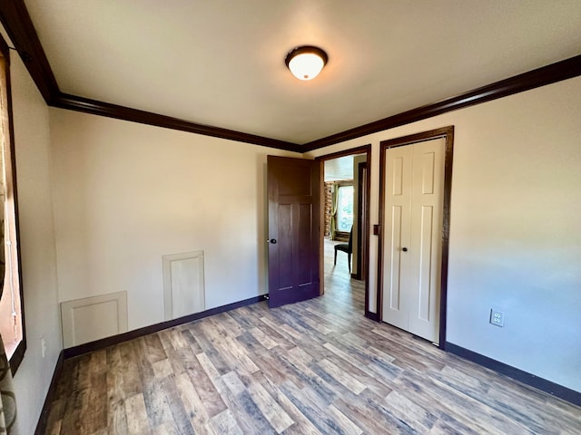 unfurnished room with ornamental molding and light wood-type flooring