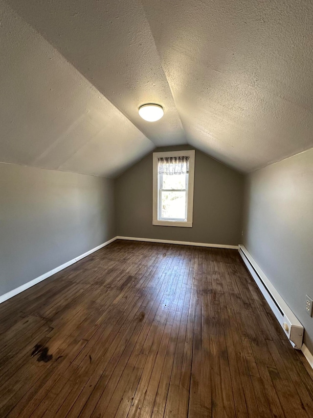 bonus room featuring vaulted ceiling, a baseboard heating unit, a textured ceiling, and dark hardwood / wood-style flooring