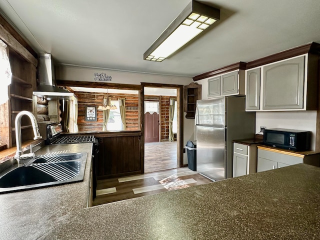 kitchen with appliances with stainless steel finishes, sink, hardwood / wood-style floors, wall chimney exhaust hood, and gray cabinets