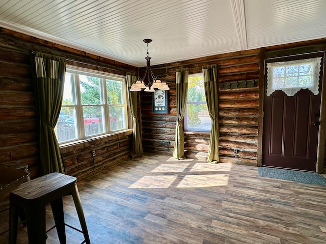 unfurnished dining area with log walls, hardwood / wood-style floors, and a healthy amount of sunlight