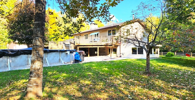 rear view of house featuring a pool side deck and a lawn