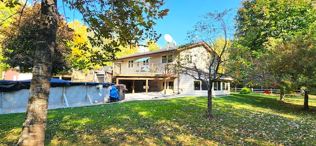 rear view of property with a yard and a swimming pool side deck