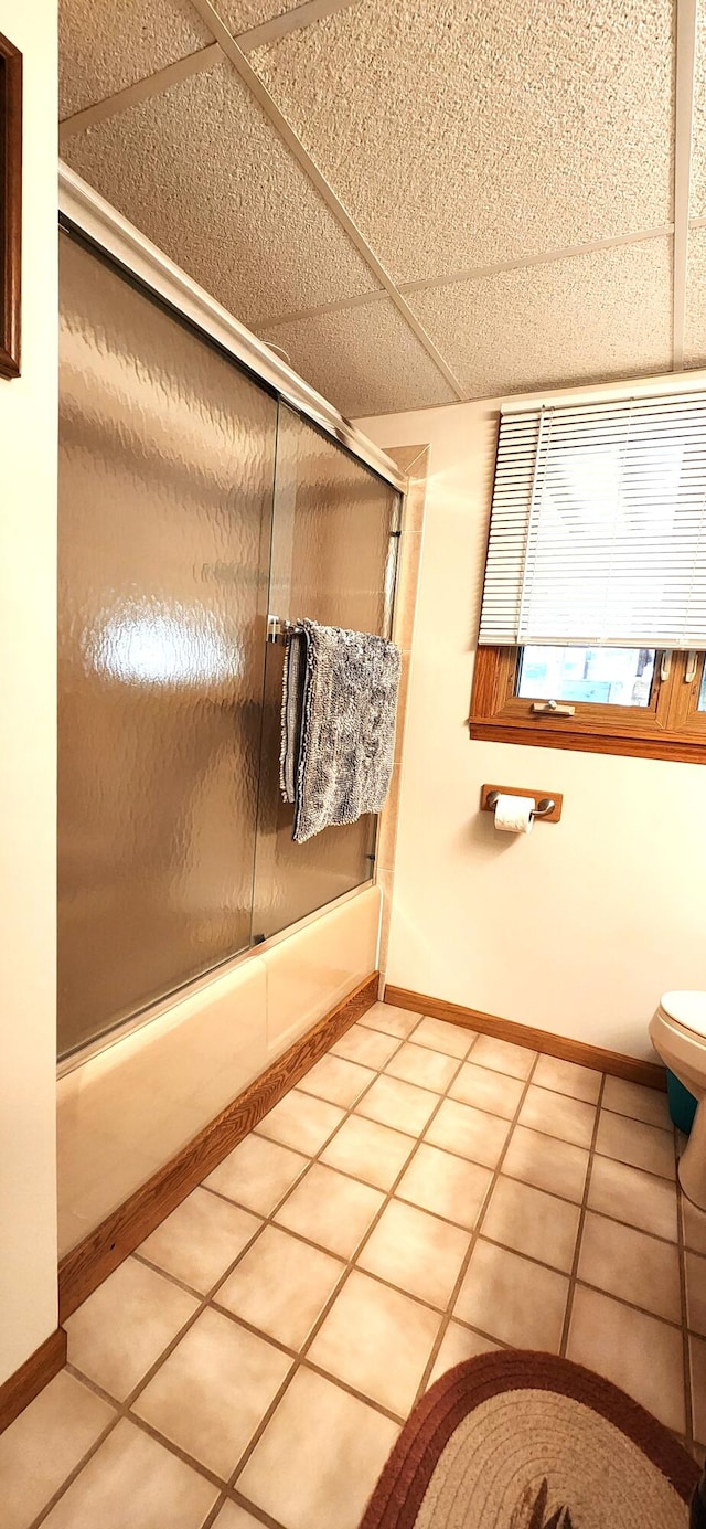 bathroom with combined bath / shower with glass door, toilet, and tile patterned floors