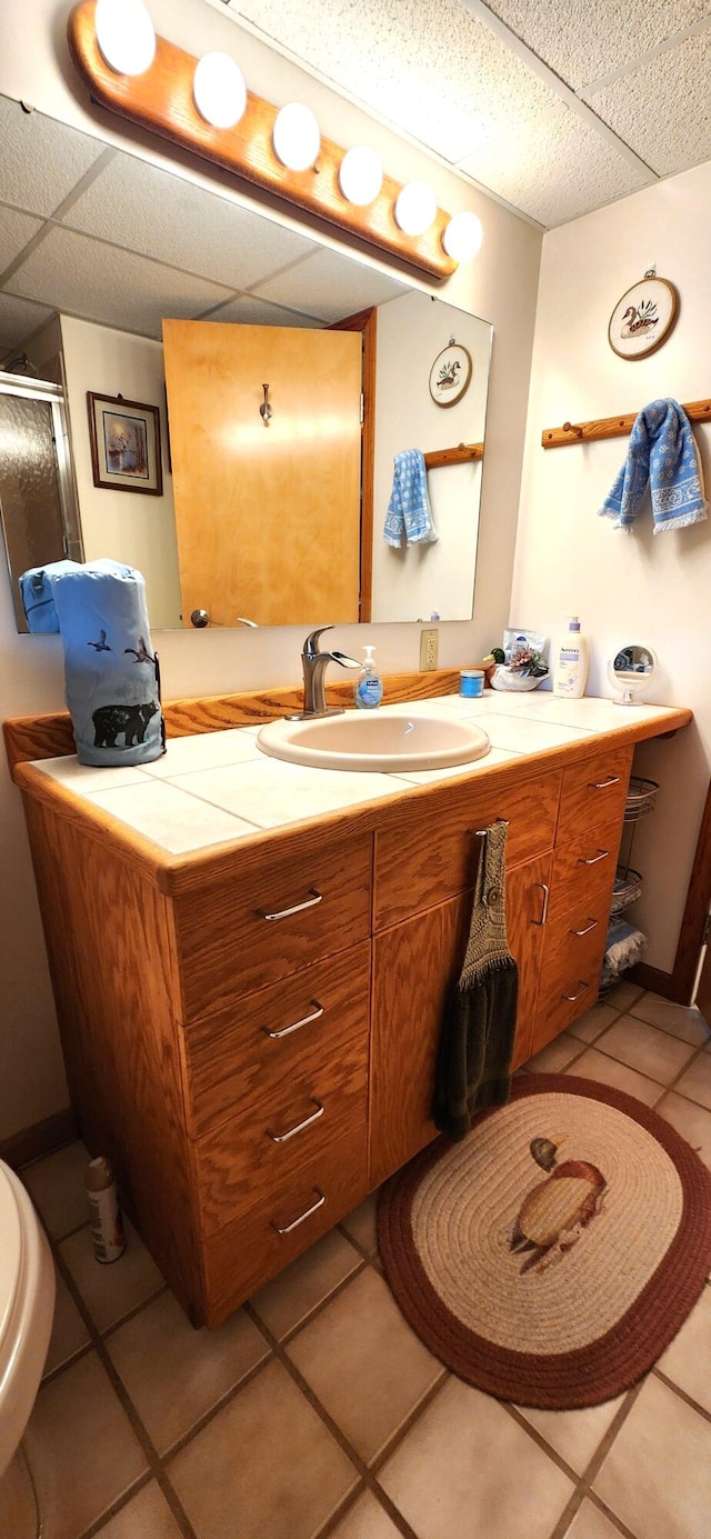 bathroom with tile patterned flooring, a shower with shower door, vanity, and toilet