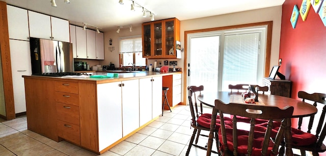 kitchen featuring white cabinets, stainless steel fridge, light tile patterned floors, and a kitchen island