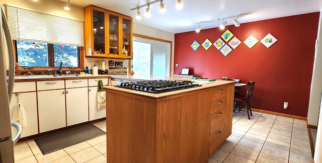 kitchen featuring rail lighting, gas cooktop, sink, and light tile patterned floors