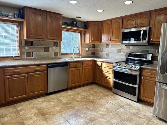 kitchen with a textured ceiling, sink, stainless steel appliances, and a wealth of natural light