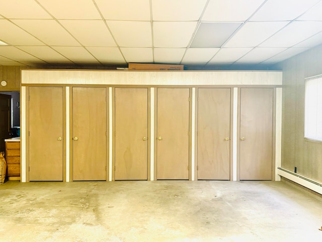 basement with a drop ceiling and a baseboard radiator