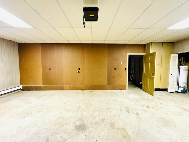 empty room with gas water heater, a drop ceiling, a baseboard radiator, and concrete floors