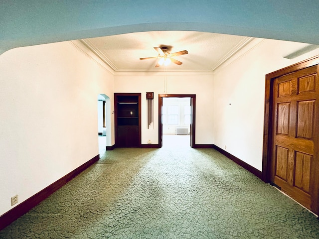 carpeted spare room featuring crown molding, ceiling fan, and radiator