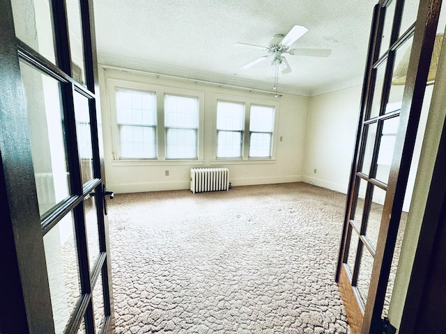 unfurnished sunroom with ceiling fan and radiator