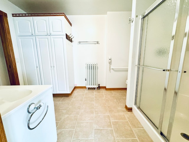 bathroom with radiator, vanity, tile patterned floors, toilet, and a shower with door