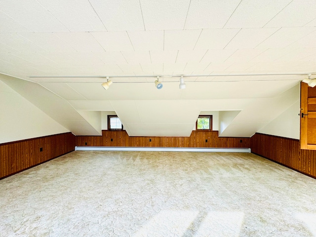 additional living space with carpet flooring, wooden walls, and vaulted ceiling