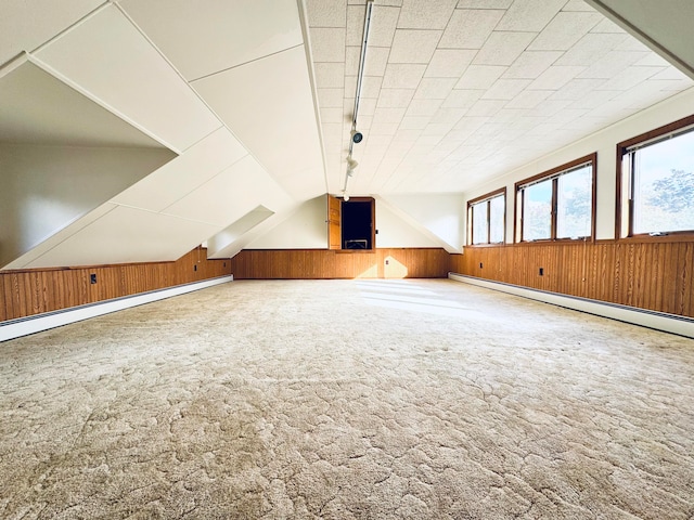 bonus room featuring lofted ceiling, a baseboard radiator, carpet floors, and wood walls