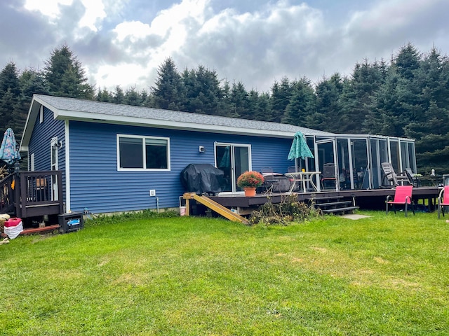 back of property featuring a sunroom, a deck, and a lawn