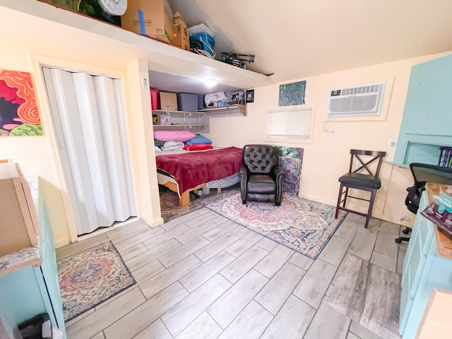 bedroom featuring lofted ceiling, a wall mounted AC, and light wood-type flooring