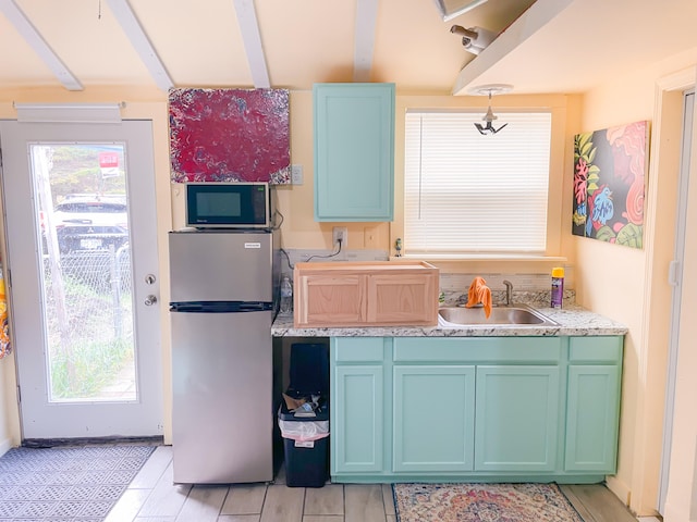 kitchen featuring plenty of natural light, beam ceiling, sink, and stainless steel appliances