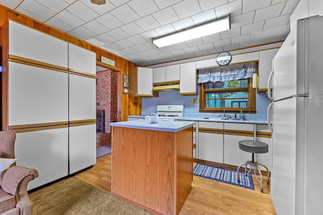 kitchen with a center island, light wood-type flooring, white appliances, and white cabinets