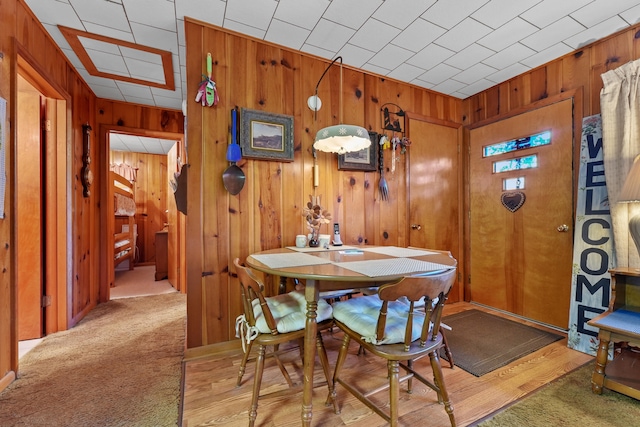 dining room with light wood-type flooring and wood walls