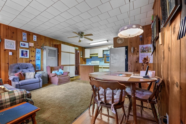 dining space featuring ceiling fan, wood walls, and hardwood / wood-style floors