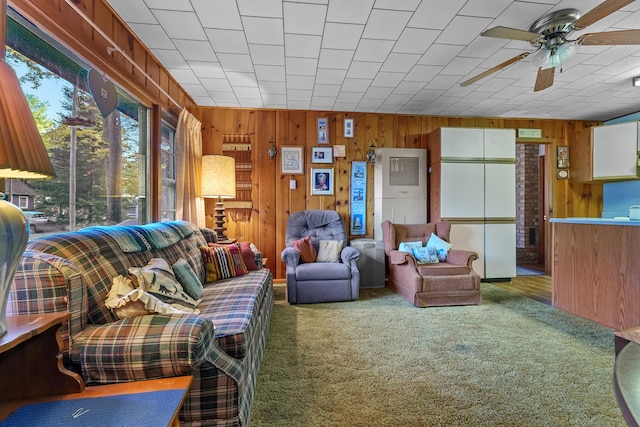 living room featuring carpet floors, wooden walls, and ceiling fan