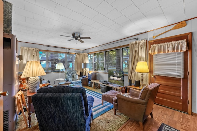 living room featuring hardwood / wood-style floors, crown molding, and ceiling fan