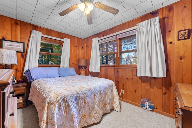 bedroom featuring carpet floors, wooden walls, and ceiling fan