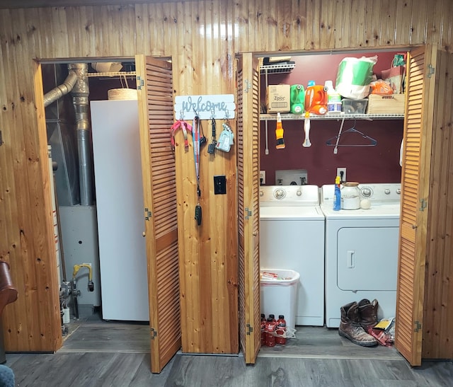 laundry area featuring washing machine and clothes dryer, dark hardwood / wood-style floors, and wooden walls