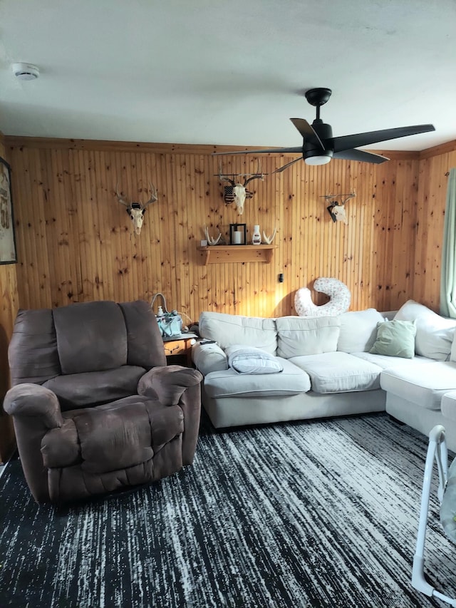 living room with crown molding, ceiling fan, and wood walls