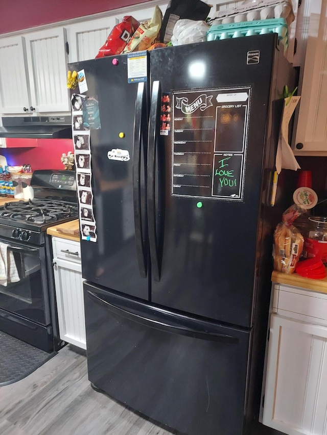 kitchen featuring white cabinets, light hardwood / wood-style flooring, and black appliances