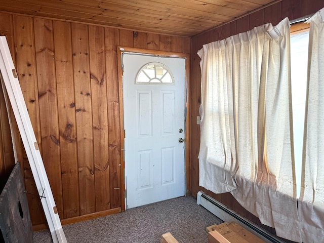 foyer entrance with wood ceiling, wood walls, baseboard heating, and carpet flooring