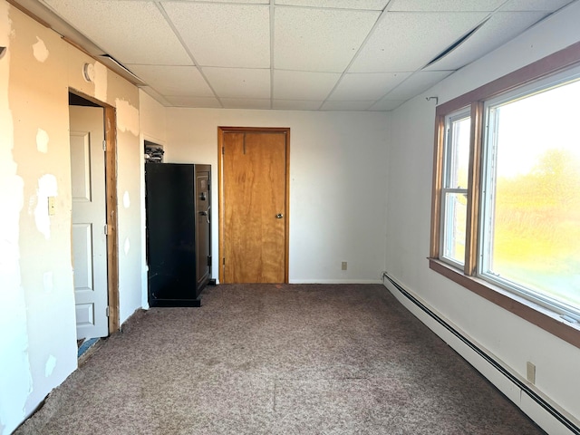 carpeted empty room with a baseboard radiator, a paneled ceiling, and a healthy amount of sunlight