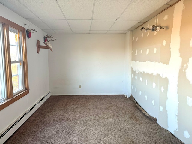 carpeted empty room featuring a drop ceiling and a baseboard heating unit