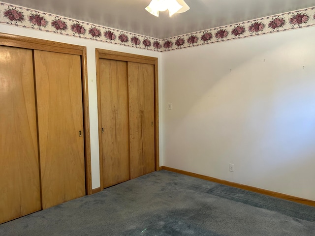 unfurnished bedroom featuring two closets, carpet flooring, and ceiling fan