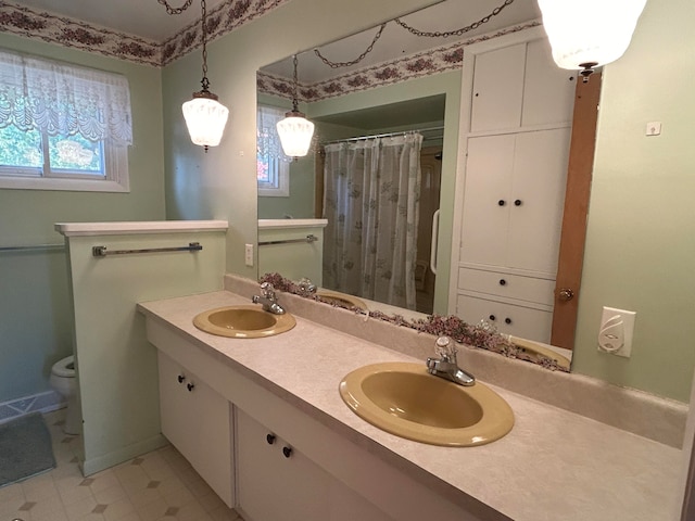 bathroom with toilet, vanity, and plenty of natural light