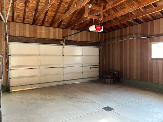 garage featuring a garage door opener and wooden walls