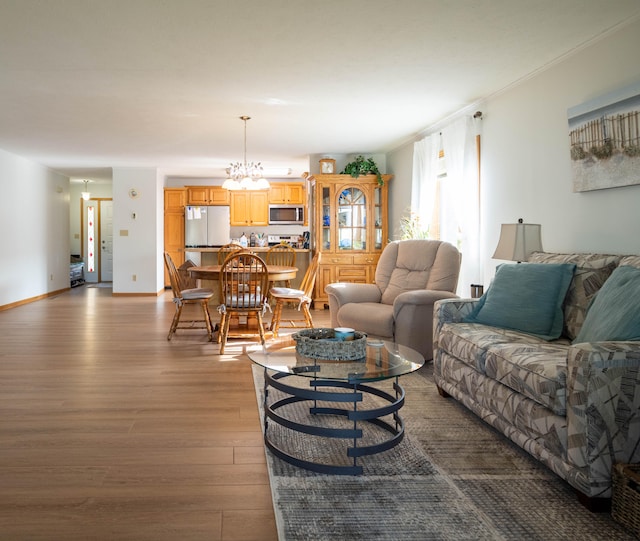 living room featuring a chandelier, light hardwood / wood-style flooring, and crown molding