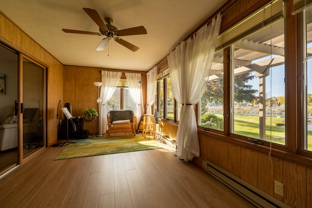 unfurnished sunroom with ceiling fan and a baseboard heating unit