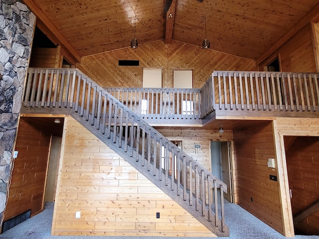 stairs with wood walls, wooden ceiling, and high vaulted ceiling