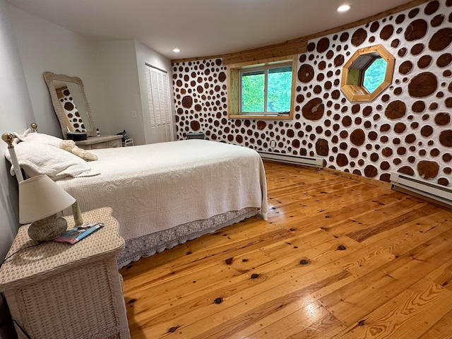 bedroom featuring a baseboard radiator, hardwood / wood-style flooring, and a closet