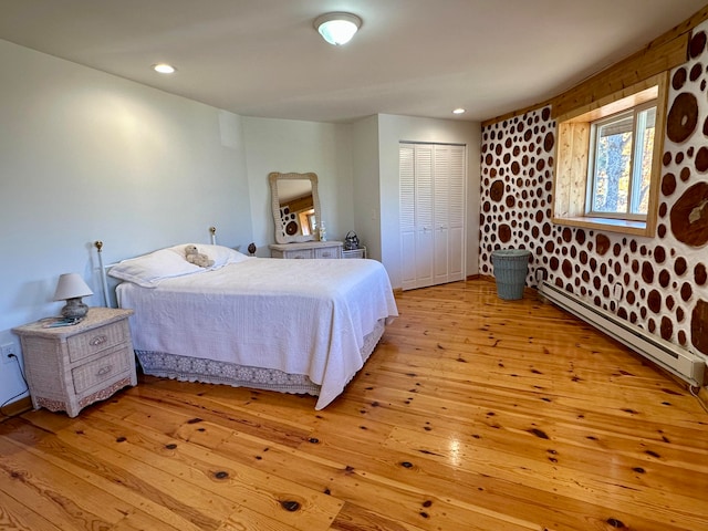 bedroom with baseboard heating, a closet, and light wood-type flooring