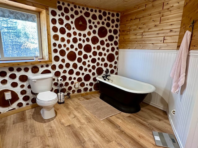 bathroom with wood ceiling, hardwood / wood-style flooring, toilet, a washtub, and wooden walls