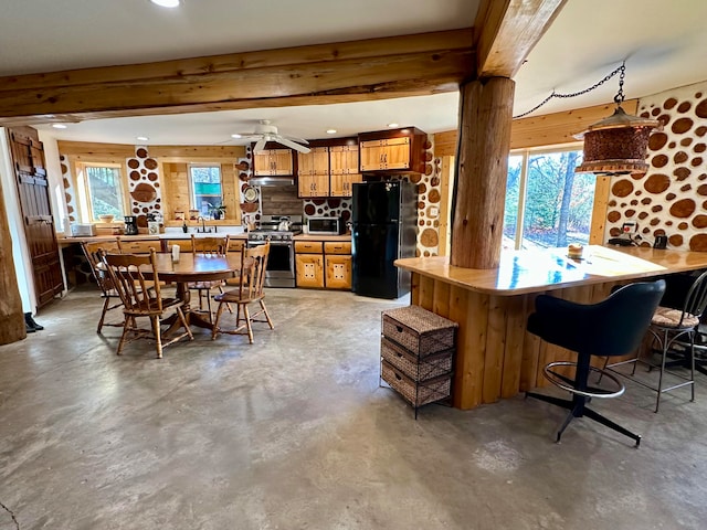 kitchen featuring appliances with stainless steel finishes, a wealth of natural light, kitchen peninsula, and beamed ceiling