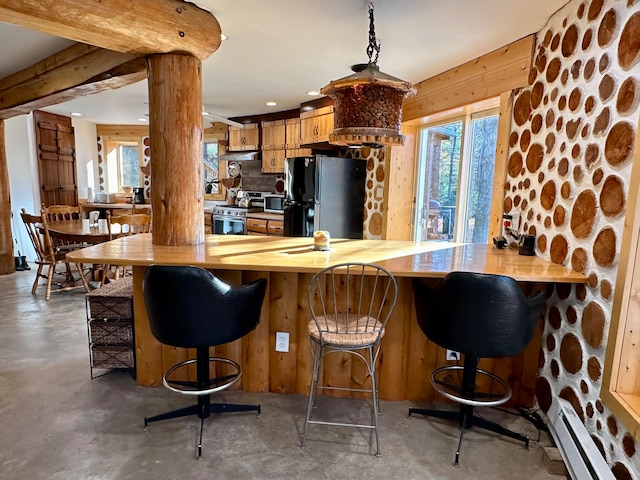 kitchen with kitchen peninsula, a baseboard heating unit, black fridge, a kitchen bar, and stainless steel gas stove