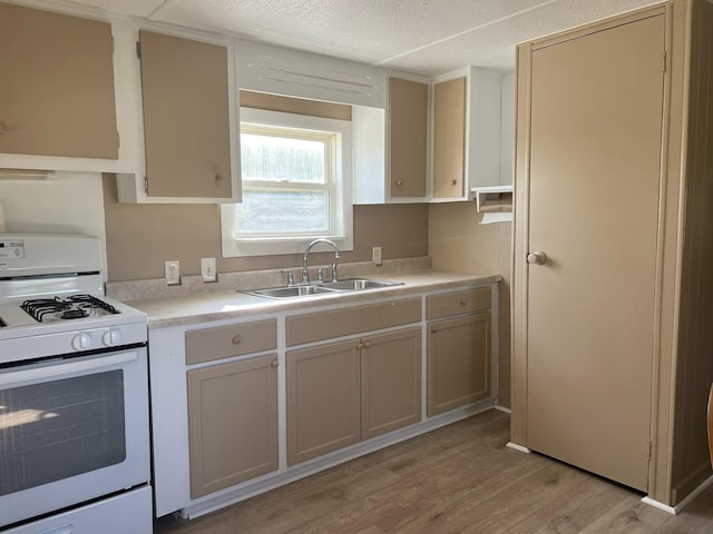 kitchen with sink, light hardwood / wood-style flooring, a textured ceiling, and gas range gas stove