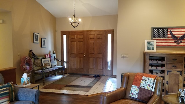 foyer entrance with lofted ceiling, wood finished floors, and an inviting chandelier