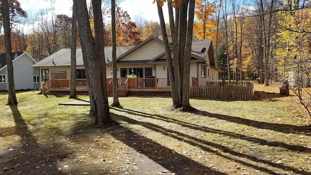 rear view of house with a wooden deck and a yard